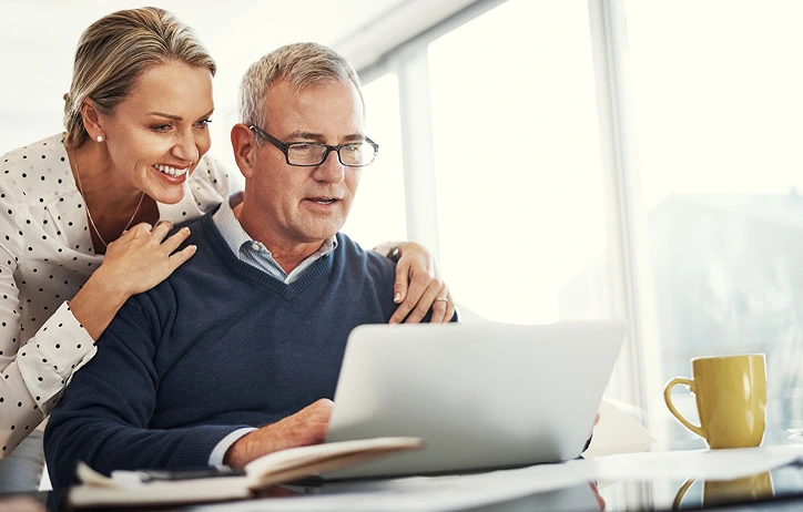 Woman looking over man's shoulder at laptop.